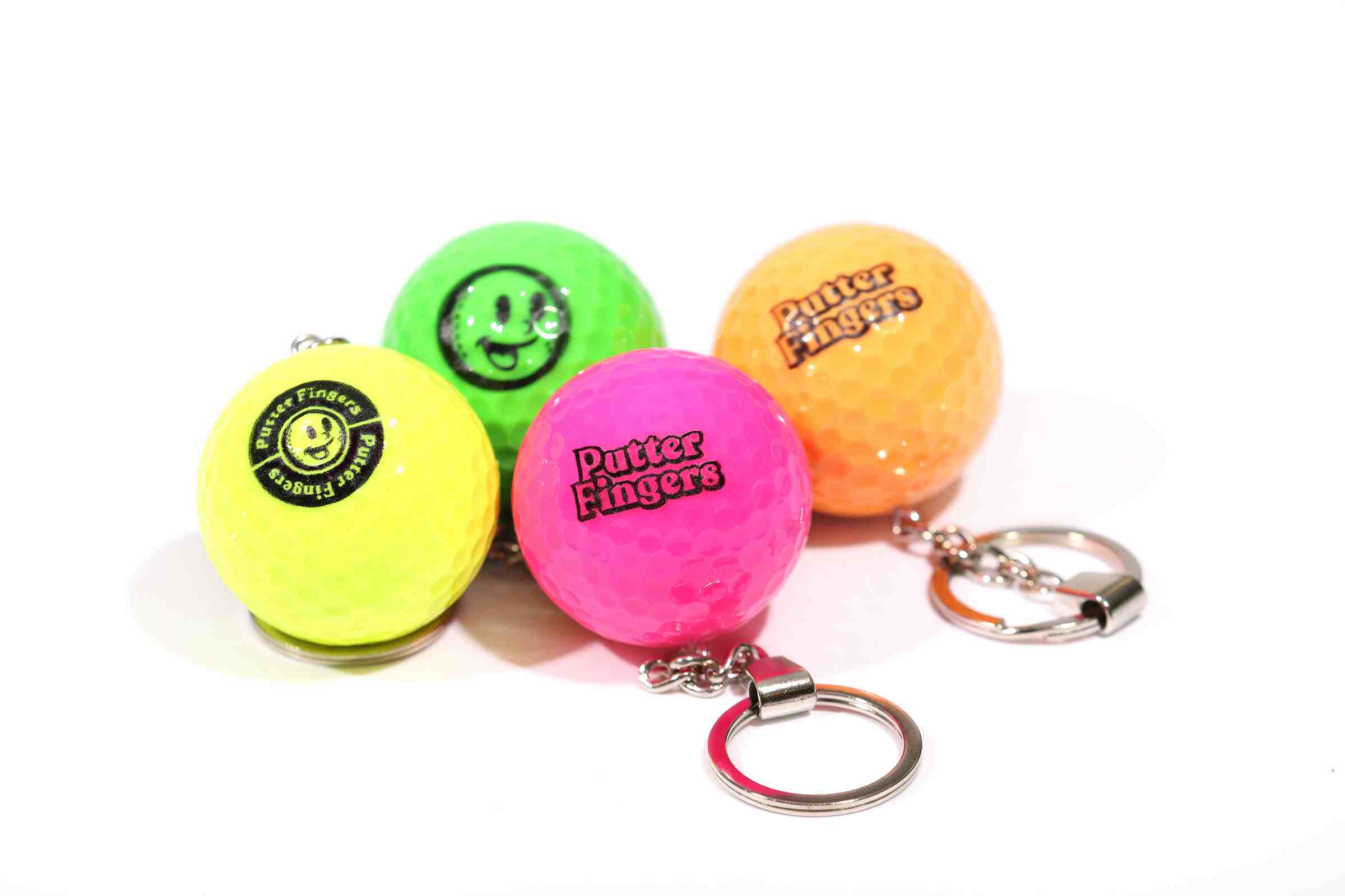 Four mini golf ball keyrings in yellow, green, pink, and orange colors, each featuring the Putterfingers logo branding on them