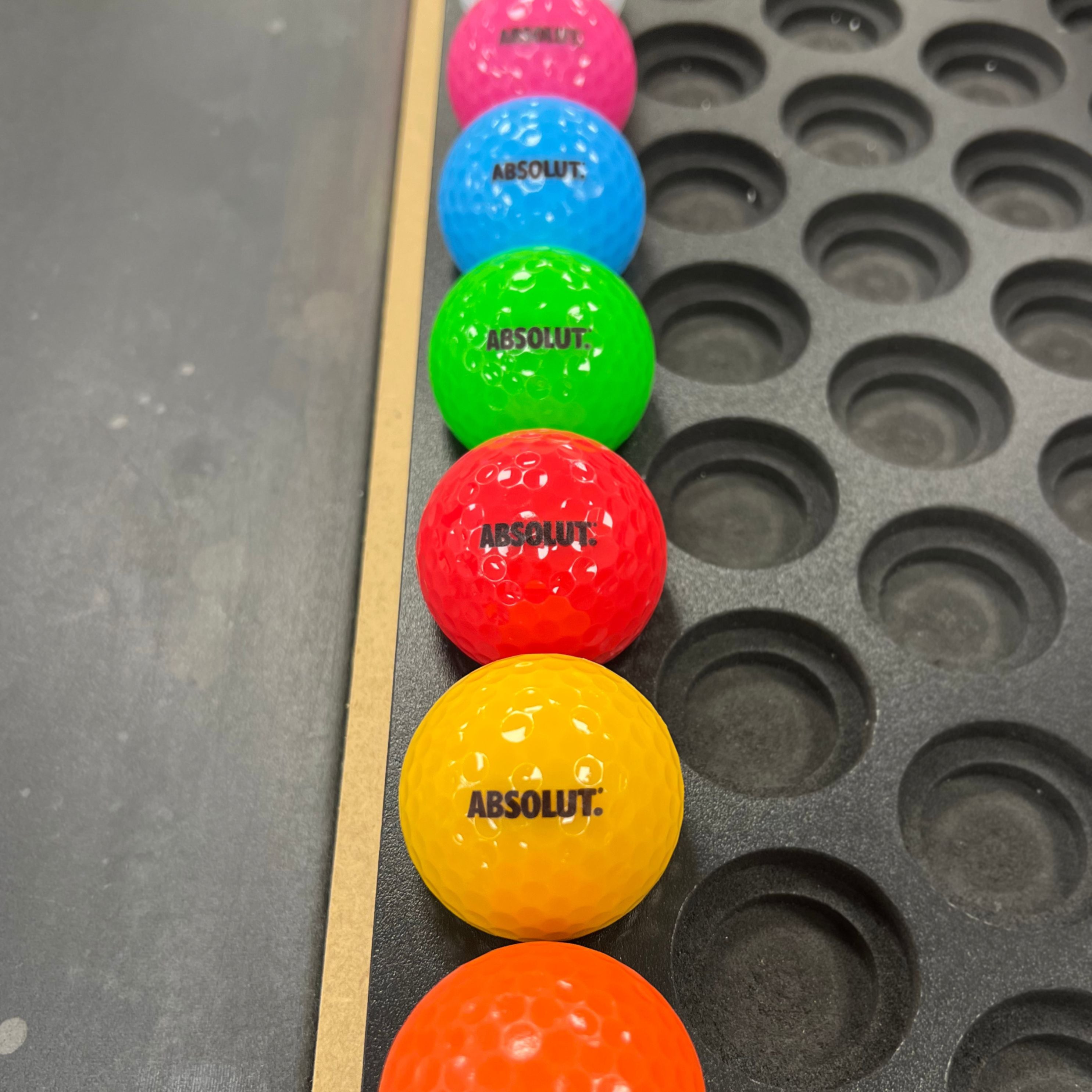Absolut logo mini golf balls lined up in range of bright colours