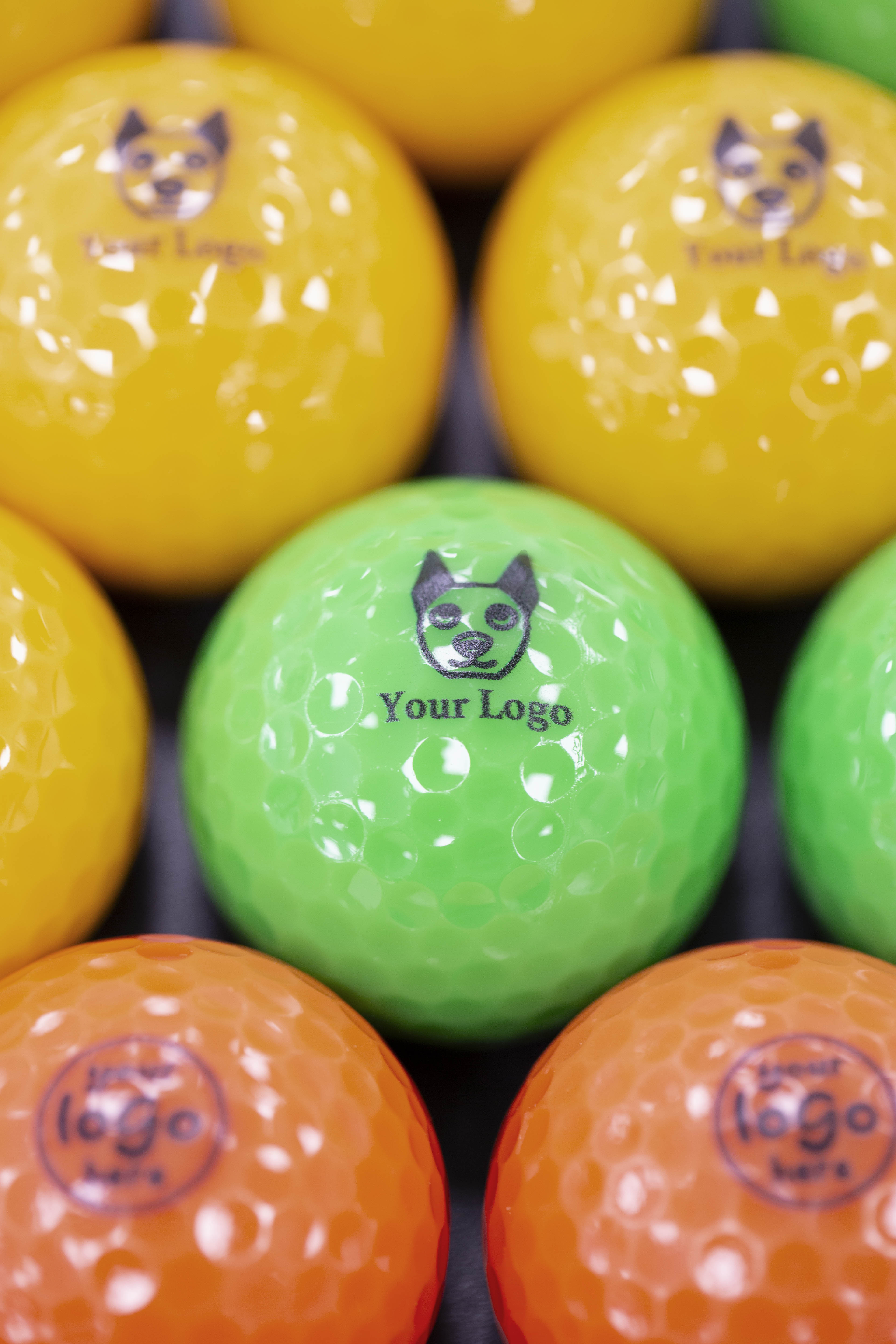 Green 'your logo' mini golf ball surrounded by orange and yellow branded mini golf balls